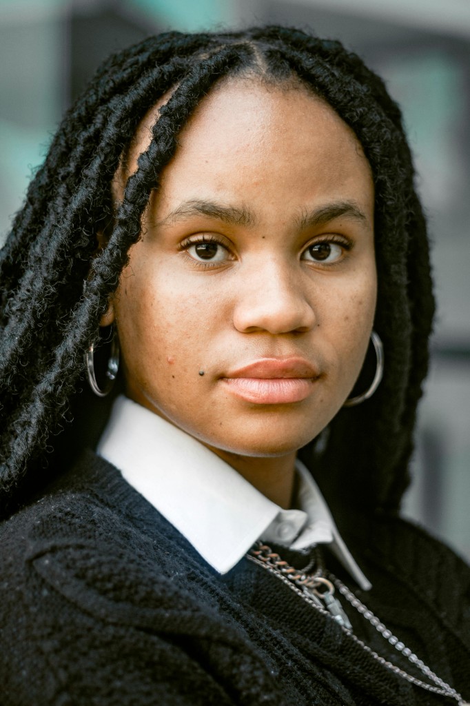 Young woman with locs in a crisp white shirt — testimonial backdrop