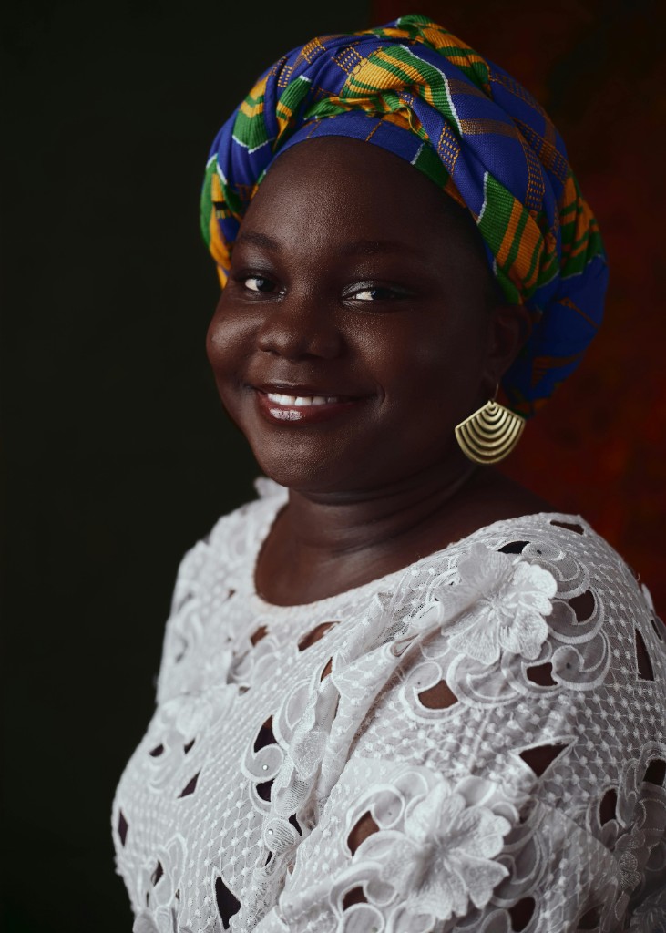 Smiling African woman in vibrant kente headwrap and white lace